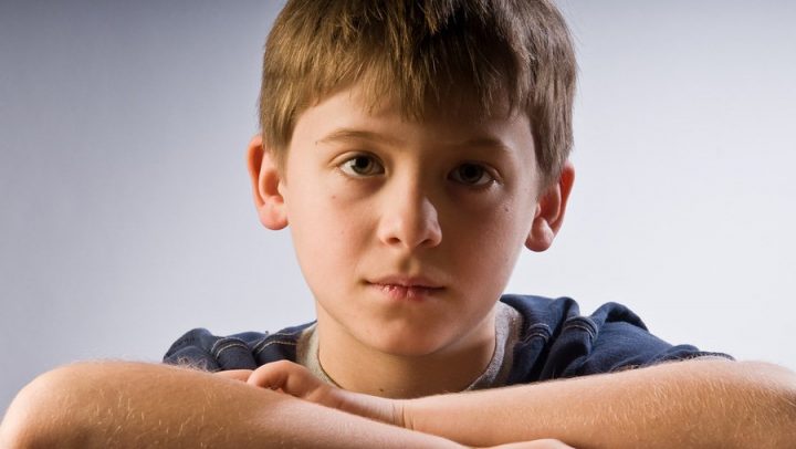 an image of a young male child looking sad or wistful. this image is being used to convey the emotional impact of divorce on younger children for a blog article on collaborative divorce
